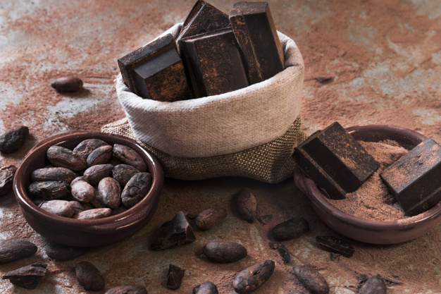 saco-de-pedacos-de-barra-de-chocolate-e-cacau-em-po-e-feijao-na-mesa-baguncada_23-2147867202